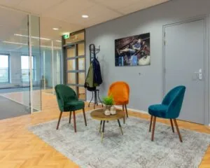 Moderne wachtruimte in kantoor aan de Fascinatio Boulevard 562 met gekleurde stoelen, glazen wanden en een kunstwerk aan de muur.