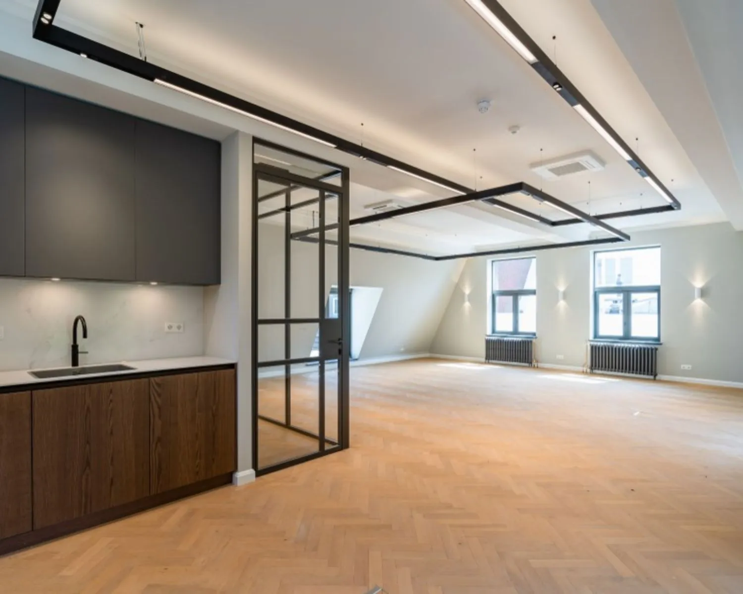 Moderne, lichte kantoorruimte met houten visgraatvloer, glazen scheidingswand en pantry aan de Herengracht 174 in Amsterdam.