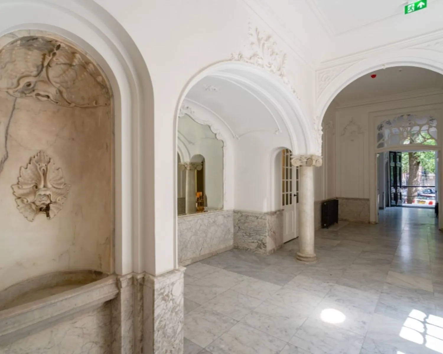 Luxe marmeren entreehal met sierlijke bogen en ornamenten in een kantoorpand aan de Herengracht 174 in Amsterdam.