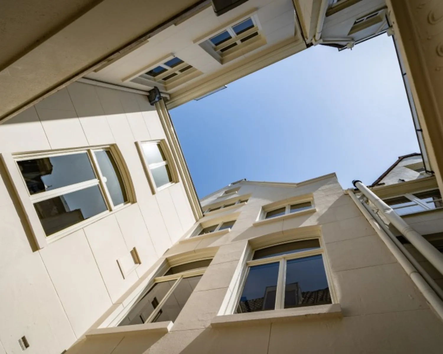 Doorkijk naar blauwe lucht vanaf de binnenplaats van het kantoorpand aan de Herengracht 174 in Amsterdam.