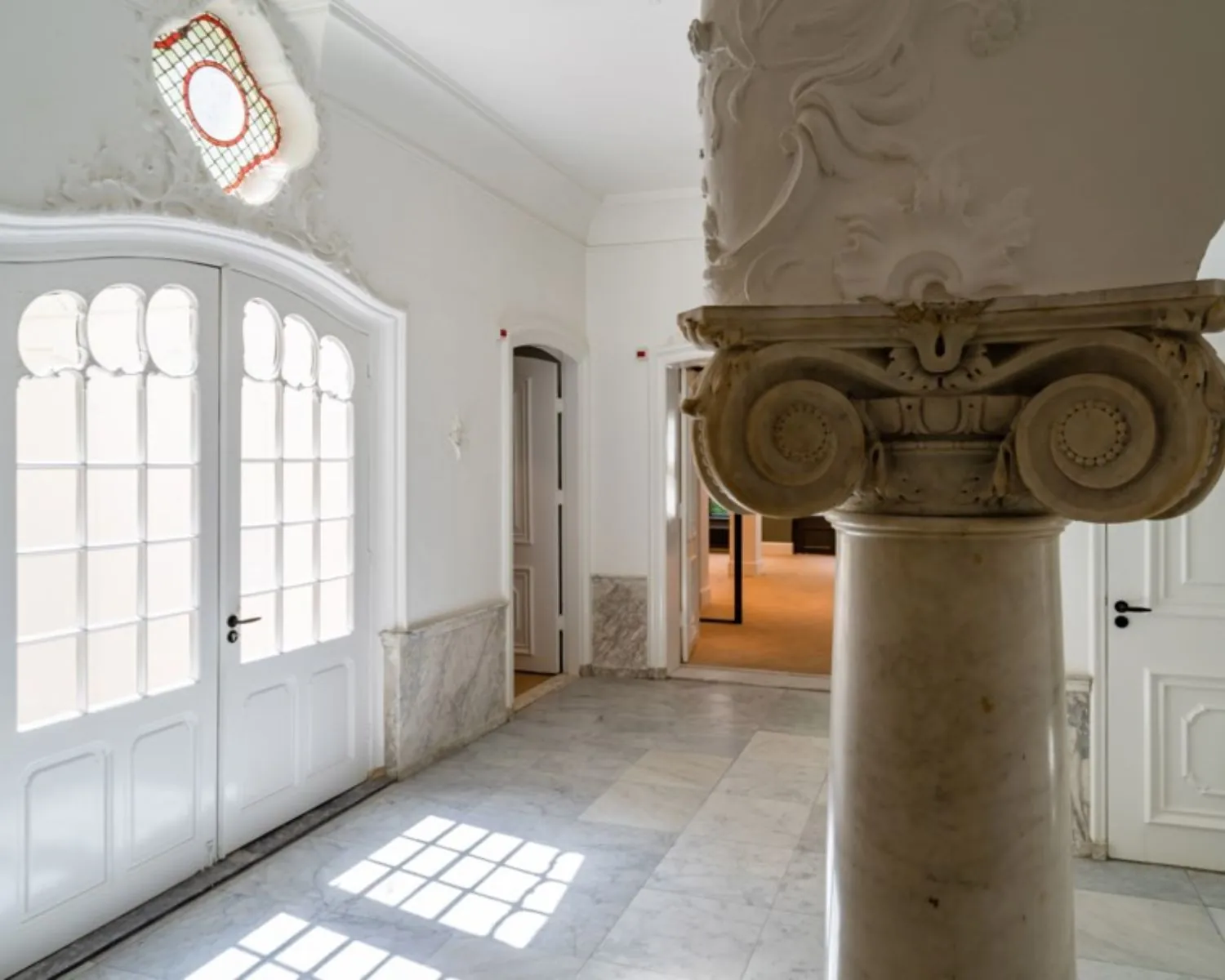 Licht en klassiek ingericht entreegebied met marmeren zuil in een kantoorruimte aan de Herengracht 174 in Amsterdam.