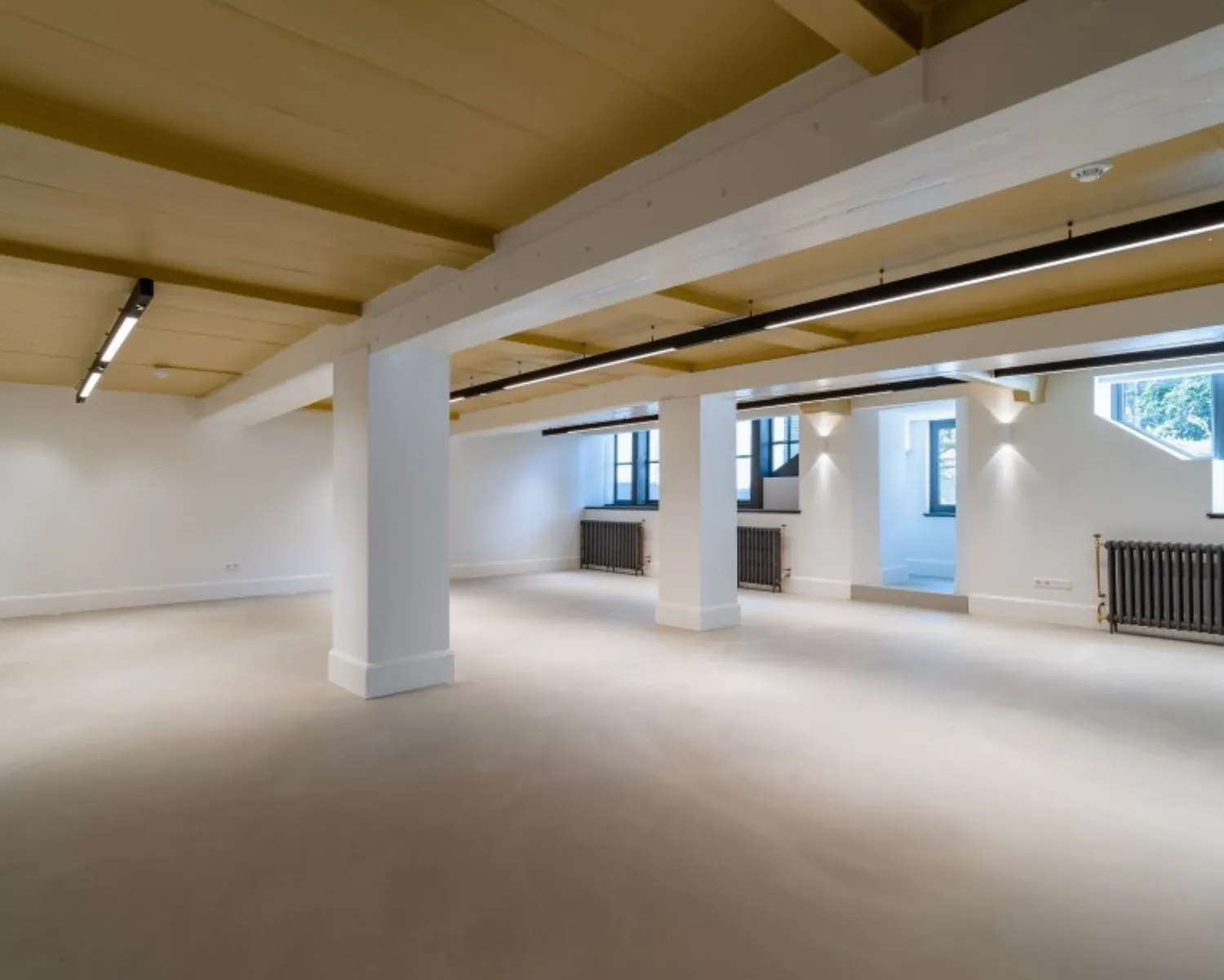 Moderne, lichte kantoorruimte met betonnen vloer en houten plafond aan de Herengracht 174 in Amsterdam.