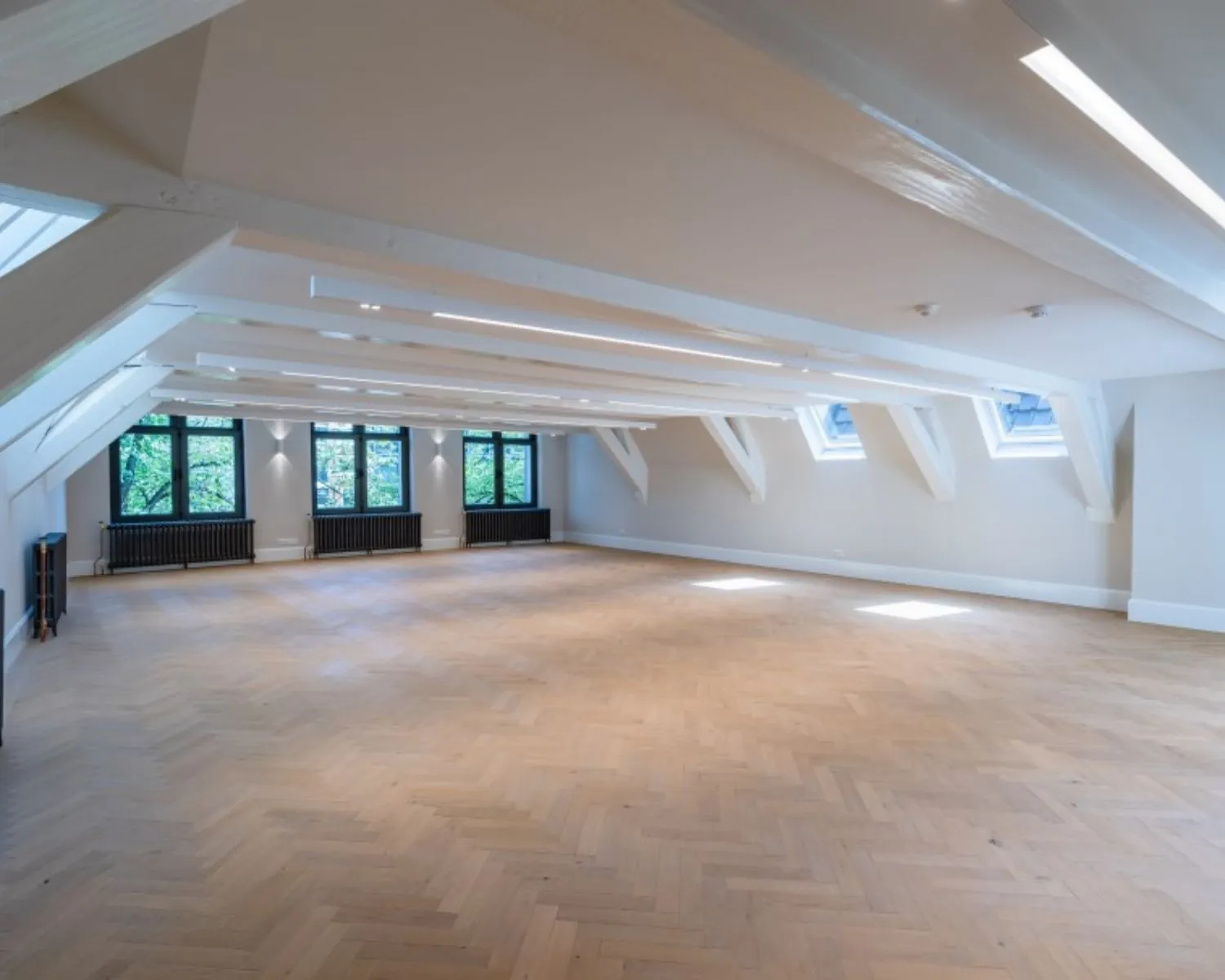 Lichte, open kantoorruimte met houten visgraatvloer en dakramen aan de Herengracht 174 in Amsterdam.