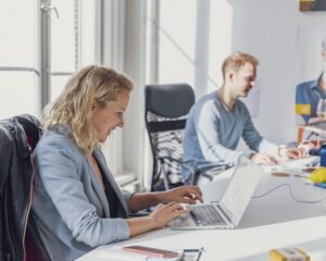 Twee mensen werken op laptops in een lichte kantoorruimte aan de Herengracht 420 in Amsterdam.