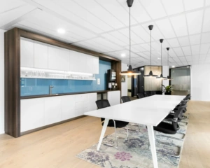 Moderne vergaderruimte met lange witte tafel, zwarte stoelen en een kitchenette aan de Johan Cruijff Boulevard.