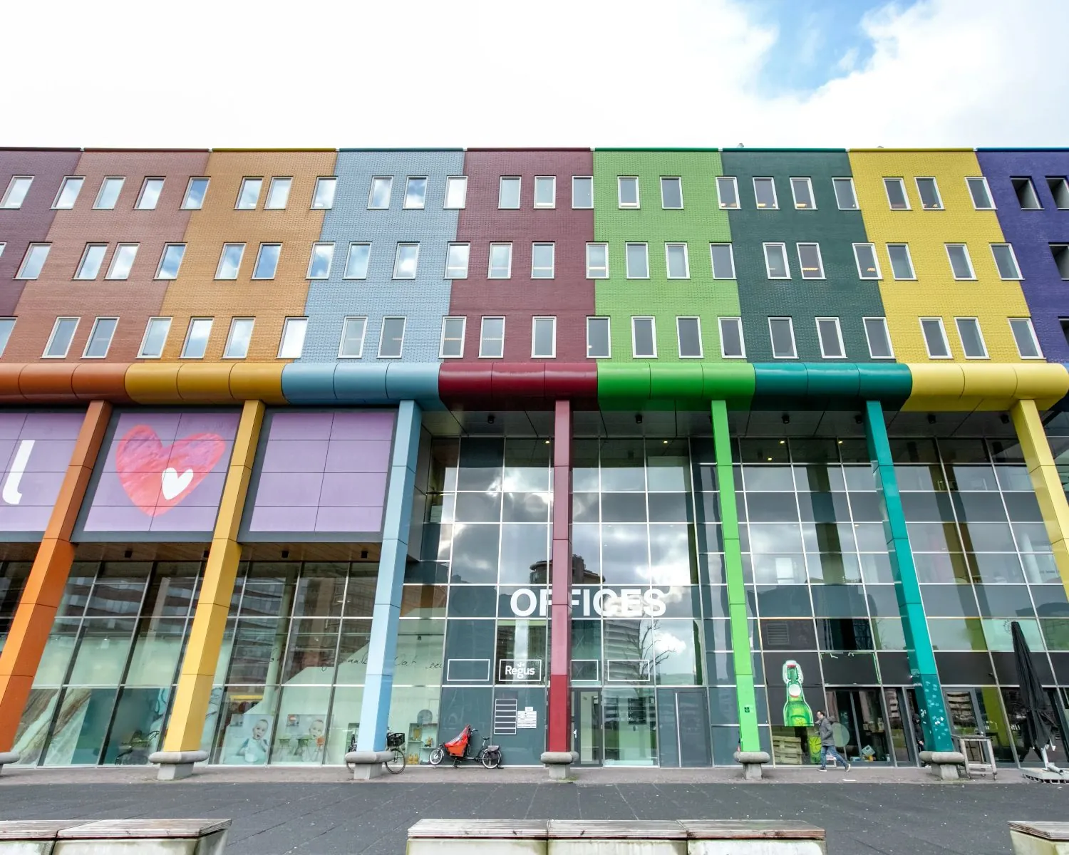 Kleurrijk kantoorgebouw aan de Johan Cruijff Boulevard 9 met grote ramen en het woord "OFFICES" op de gevel.