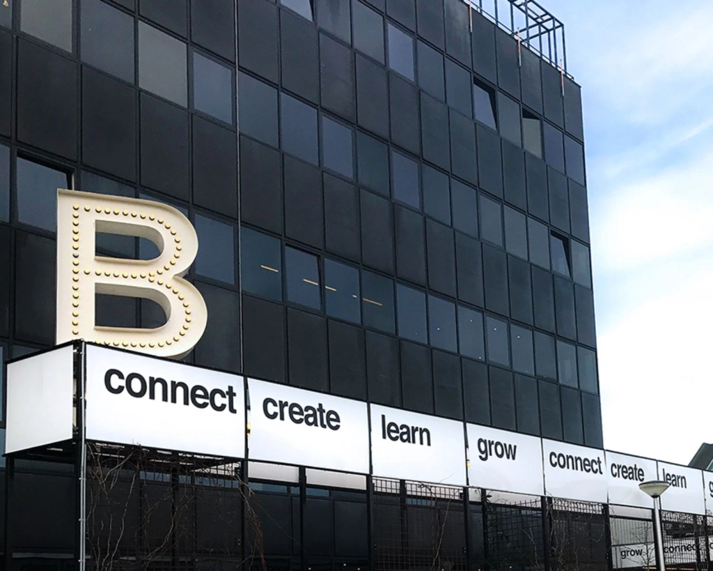 Gevel van het kantoorgebouw aan de Johan Huizingalaan 763A in Amsterdam met grote letter B en woorden als "connect", "create", "learn" en "grow".