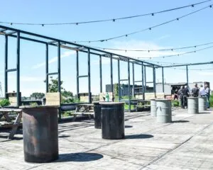 Dakterras met picknicktafels, olievaten als statafels en uitzicht op de omgeving bij Johan Huizingalaan 763A in Amsterdam.