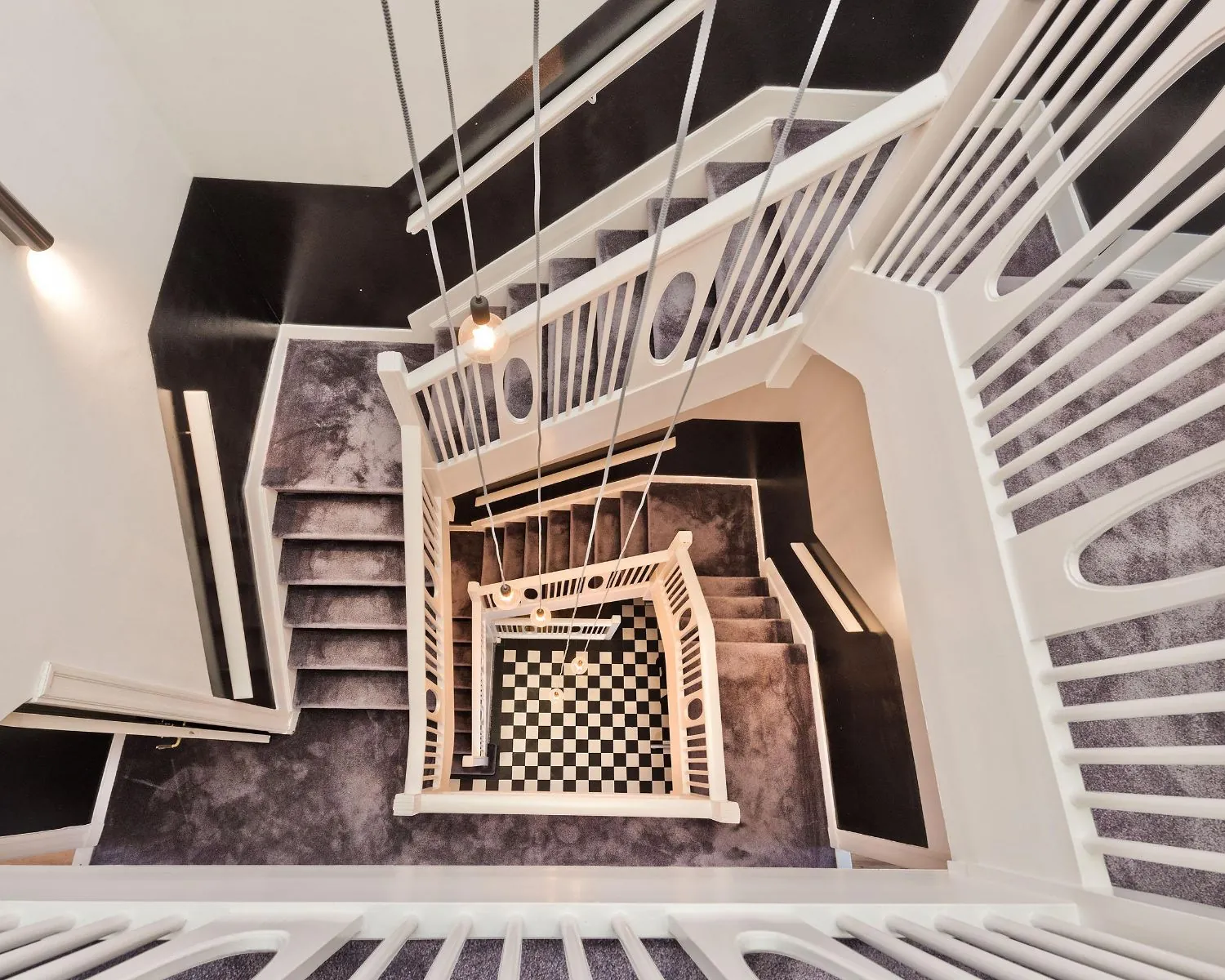 Trapgat met witgelakte leuningen en paarse vloerbedekking in een kantoor aan de Johannes Vermeerstraat 55 in Amsterdam.