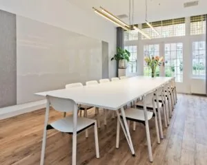 Moderne vergaderruimte met lange witte tafel en witte stoelen aan de Johannes Vermeerstraat 55 in Amsterdam.