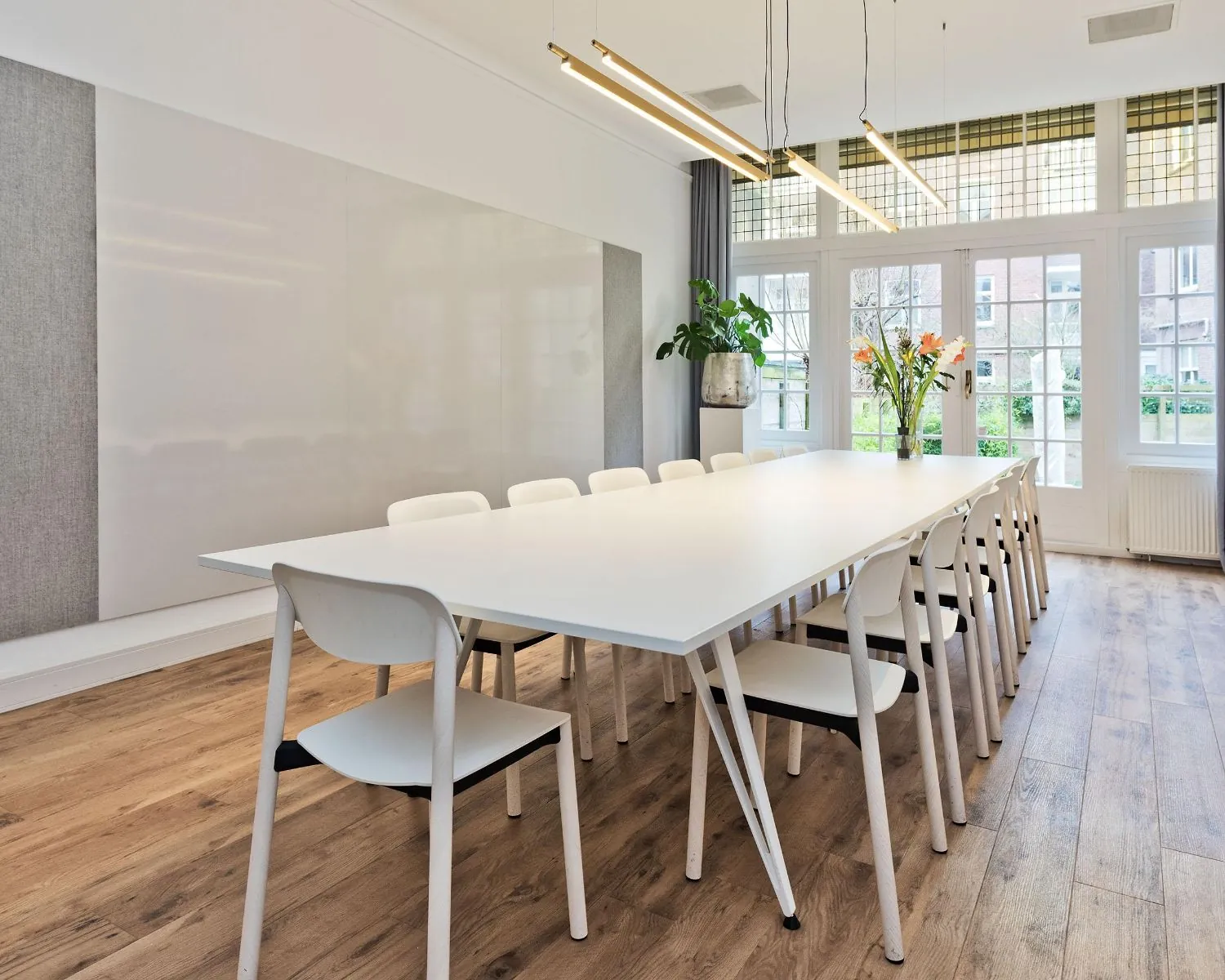 Moderne vergaderruimte met lange witte tafel en witte stoelen aan de Johannes Vermeerstraat 55 in Amsterdam.
