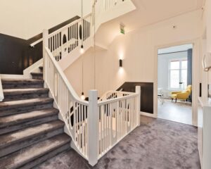 Trapportaal met modern wit hekwerk en tapijt in een kantoorpand aan de Johannes Vermeerstraat 55 in Amsterdam.