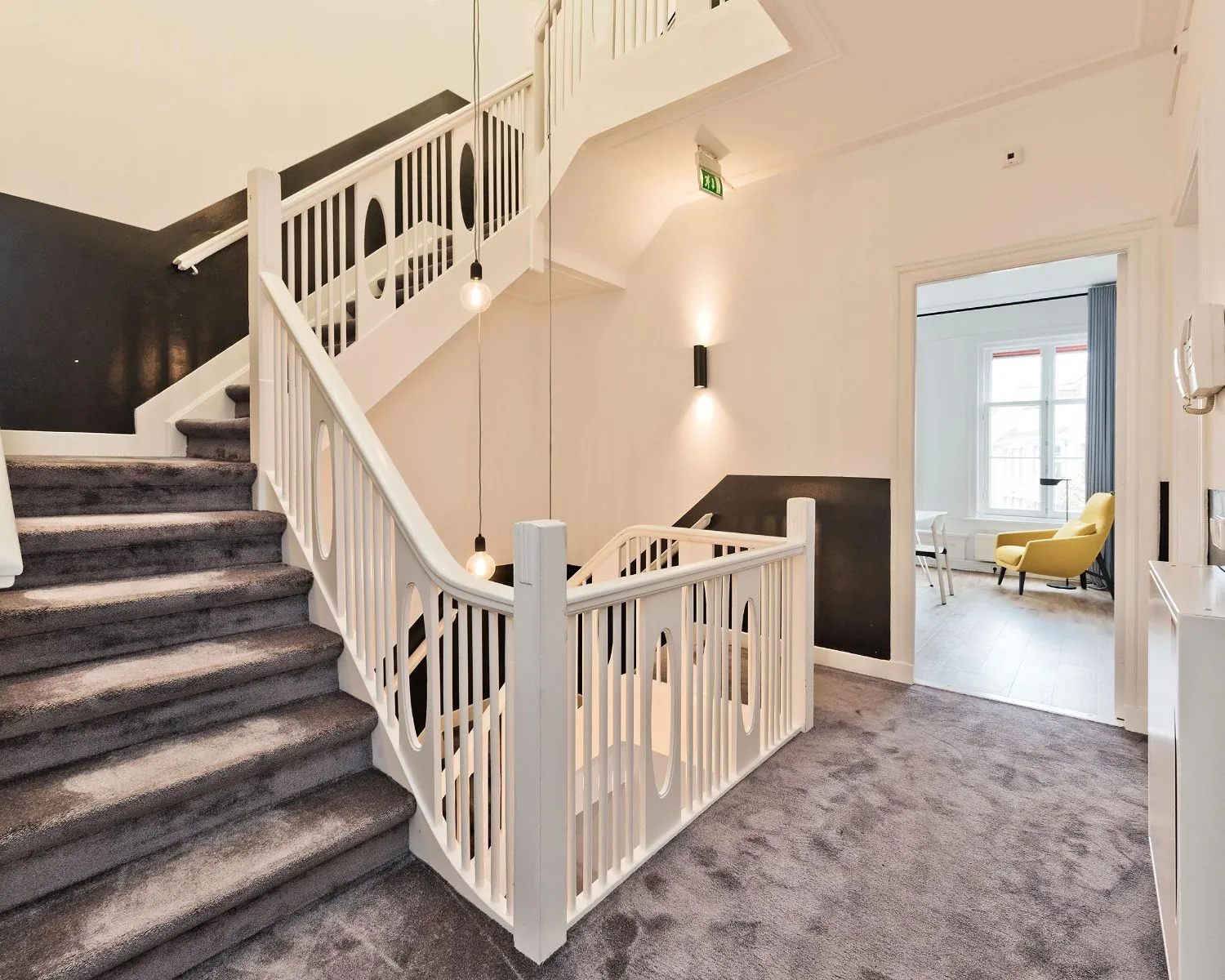 Trapportaal met modern wit hekwerk en tapijt in een kantoorpand aan de Johannes Vermeerstraat 55 in Amsterdam.