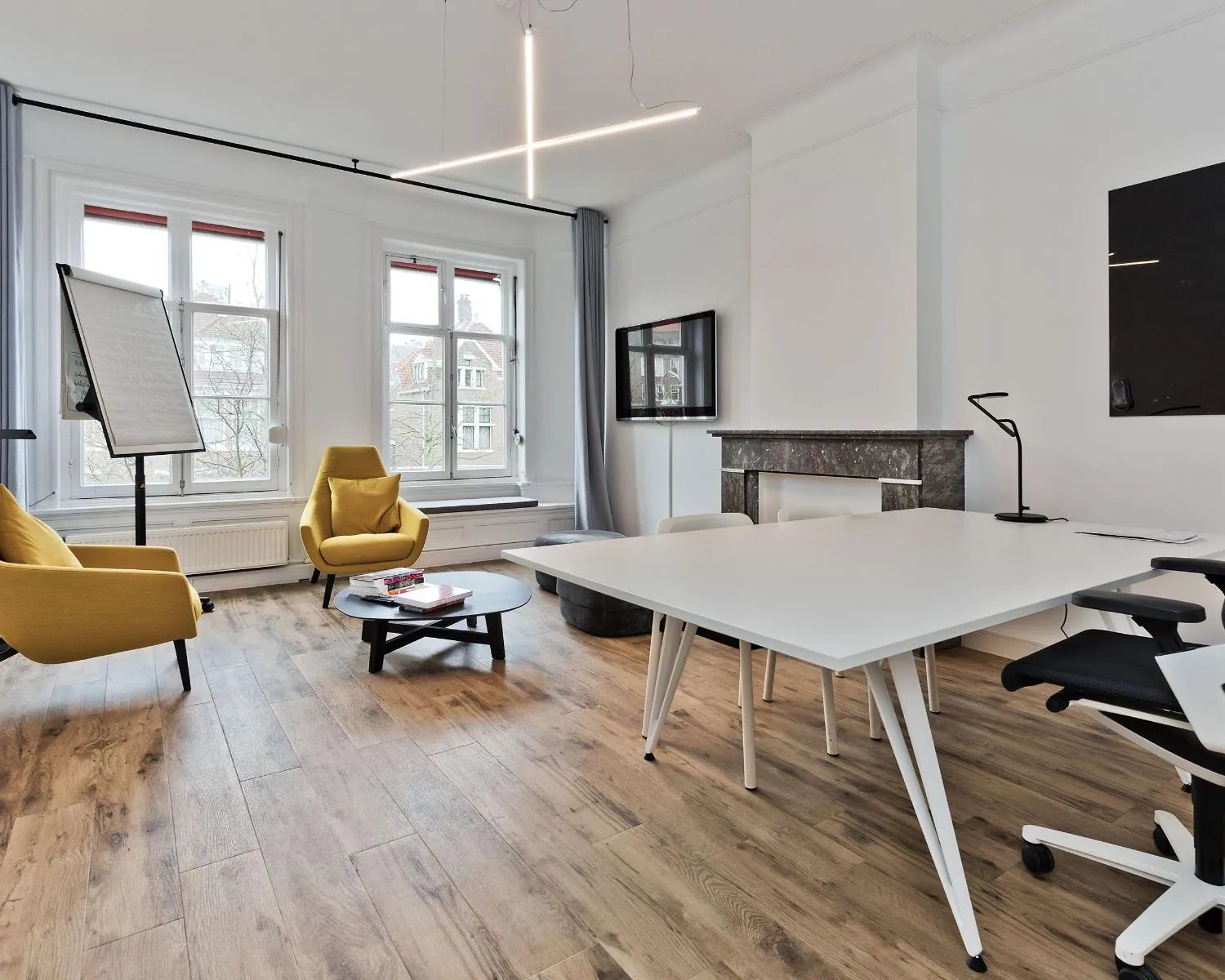 Moderne en lichte kantoorruimte met houten vloer, gele fauteuils, een vergadertafel en grote ramen aan de Johannes Vermeerstraat 55 in Amsterdam.