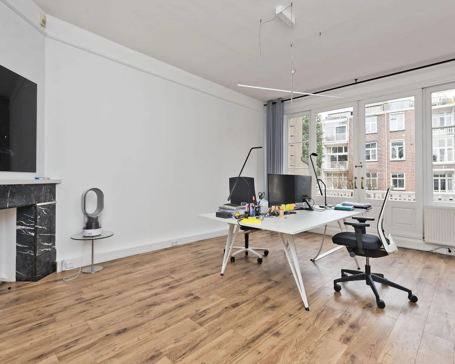 Moderne kantoorruimte met twee werkplekken en grote ramen aan de Johannes Vermeerstraat 55 in Amsterdam.