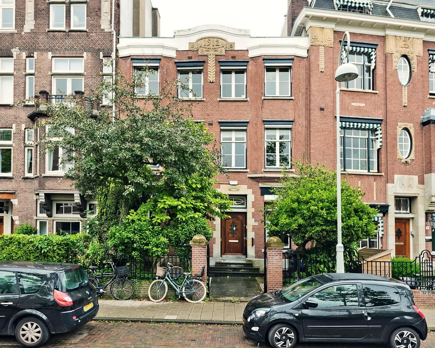 Voorgevel van een klassiek kantoorpand aan de Johannes Vermeerstraat 55 in Amsterdam met bakstenen gevel, bomen en geparkeerde auto's.