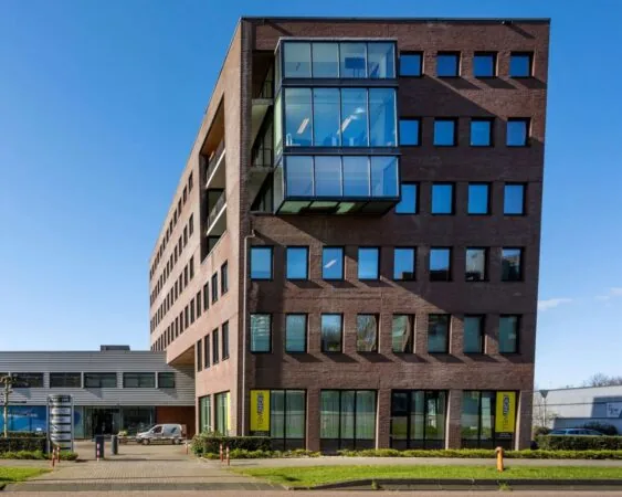 Modern kantoorgebouw aan de Joop Geesinkweg 140-199 in Amsterdam met bakstenen gevel en glazen uitbouw.