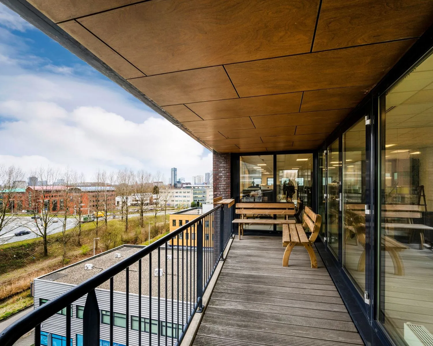 Balkon met houten bankjes en uitzicht op kantoren aan de Joop Geesinkweg 140-199 in Amsterdam.
