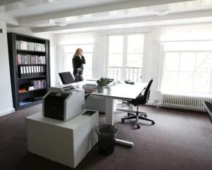 Moderne kantoorruimte aan de Keizersgracht met bureaus, boekenkast en grote ramen met veel daglicht.