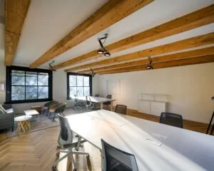 Moderne kantoorruimte aan de Keizersgracht 121 in Amsterdam met houten balkenplafond en grote werktafels.