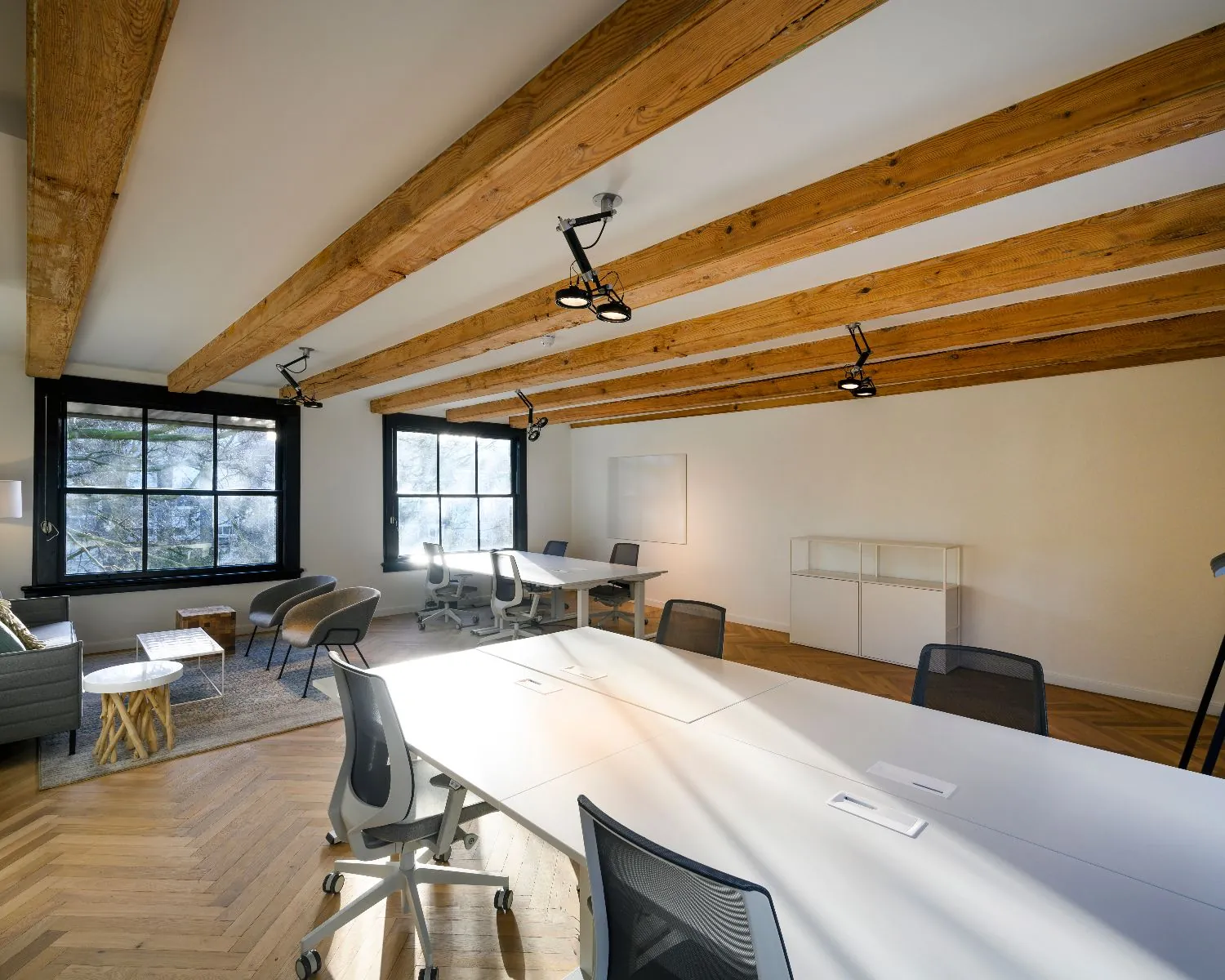 Moderne kantoorruimte aan de Keizersgracht 121 in Amsterdam met houten balkenplafond en grote werktafels.