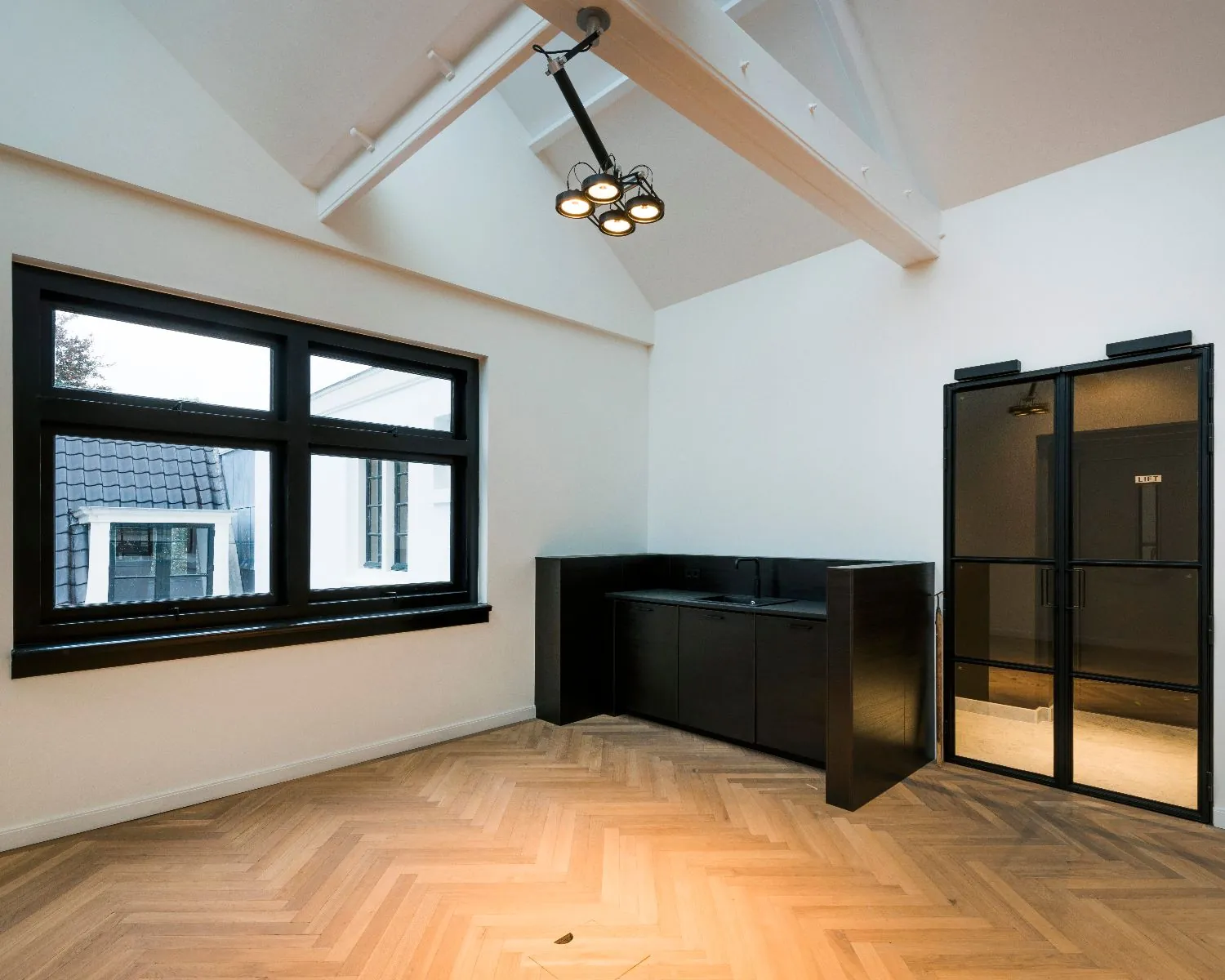Moderne kantoorruimte aan de Keizersgracht 121 in Amsterdam met hoog plafond, zwarte stalen deuren en ingebouwde kitchenette.