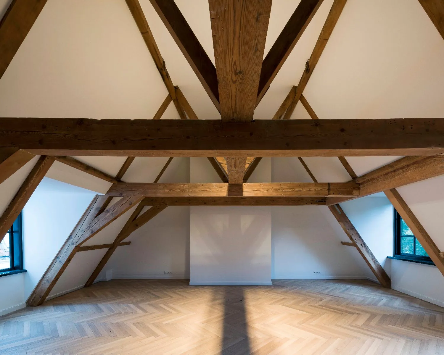 Open kantoorruimte met houten balken en visgraatvloer aan de Keizersgracht 121 in Amsterdam.