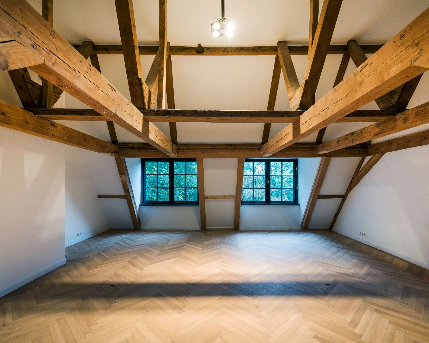 Lichte kantoorruimte met houten balkenplafond en visgraatvloer aan de Keizersgracht 121 in Amsterdam.