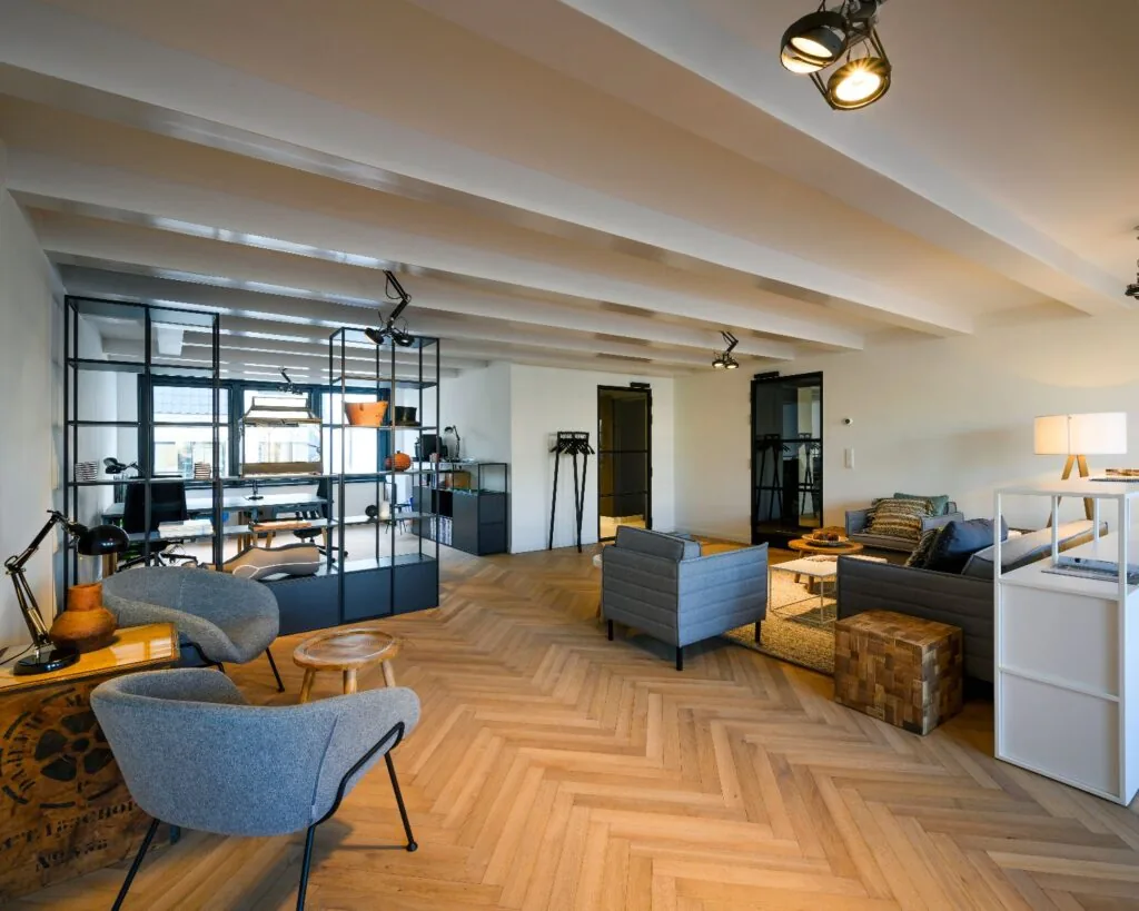 Moderne en sfeervol ingerichte kantoorruimte aan de Keizersgracht 121 in Amsterdam met zithoeken, glazen scheidingswand en houten visgraatvloer.