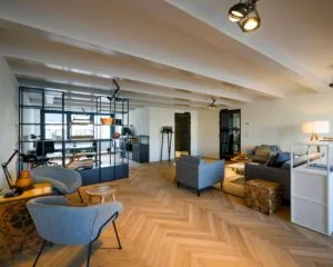 Moderne en sfeervol ingerichte kantoorruimte aan de Keizersgracht 121 in Amsterdam met zithoeken, glazen scheidingswand en houten visgraatvloer.