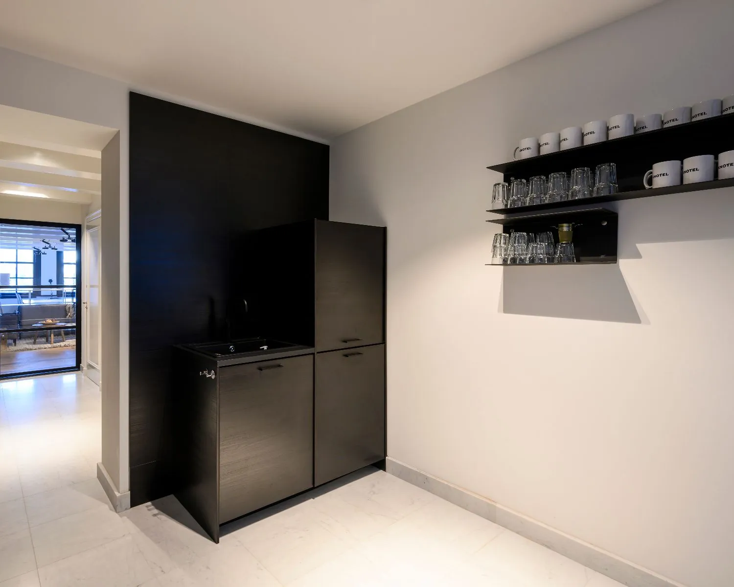 Moderne kantoorpantry met zwarte kasten, glazen en koffiemokken aan de Keizersgracht 121 in Amsterdam.