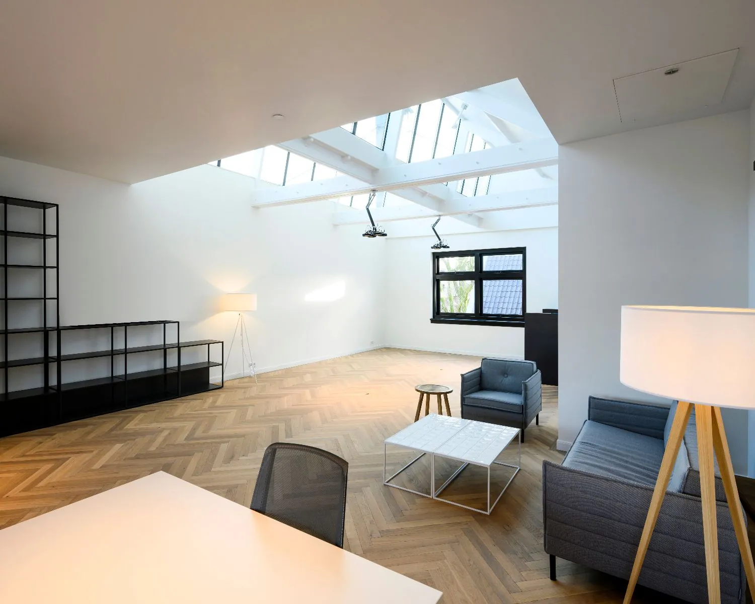 Moderne en lichte kantoorruimte aan de Keizersgracht 121 in Amsterdam met houten visgraatvloer, zitgedeelte en grote dakramen.