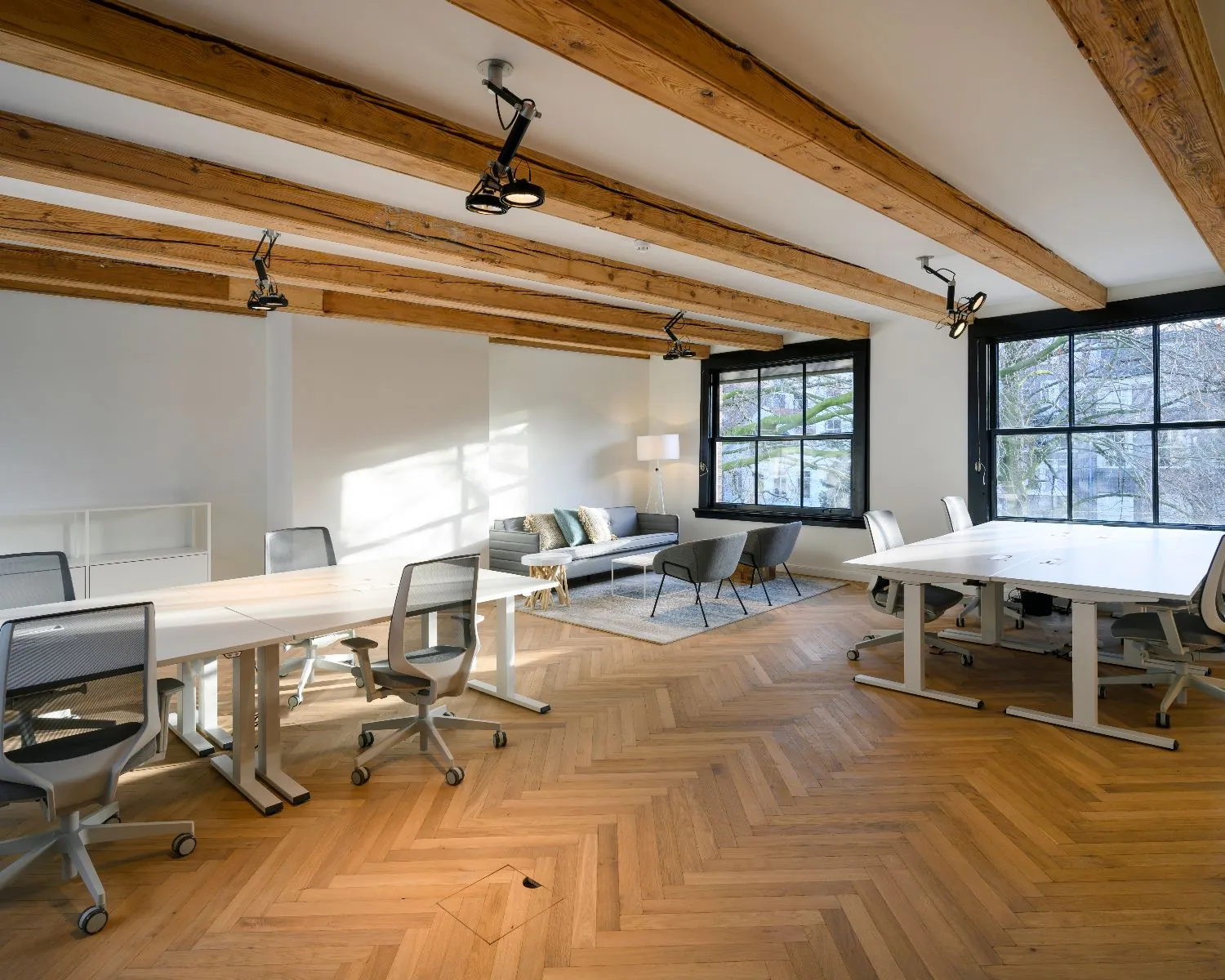 Moderne kantoorruimte aan de Keizersgracht 121 in Amsterdam met houten vloer, balkenplafond, werkplekken en zithoek.