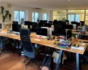 Moderne, open kantoorruimte aan de Keizersgracht 205 in Amsterdam met lange houten bureaus en meerdere werkplekken met iMacs.