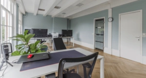 Moderne, lichte kantoorruimte aan de Keizersgracht 321 in Amsterdam met bureaus, computers en een houten visgraatvloer.