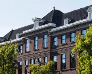 Gevel van een klassiek kantoorpand aan de Keizersgracht 617 in Amsterdam met grote ramen en een zwart pannendak.