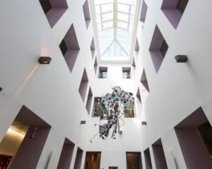 Lichte atriumruimte in kantoorpand aan de Keizersgracht 617 in Amsterdam met glazen dak en moderne kunstinstallatie.