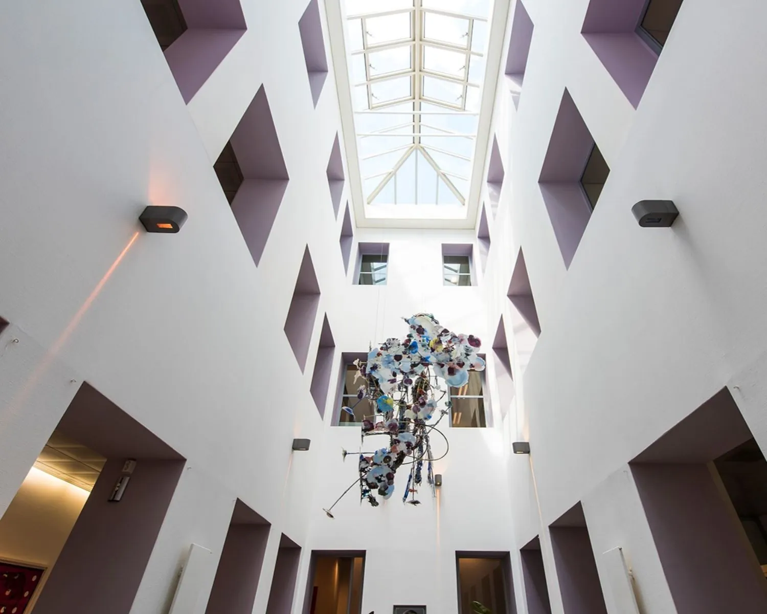 Lichte atriumruimte in kantoorpand aan de Keizersgracht 617 in Amsterdam met glazen dak en moderne kunstinstallatie.