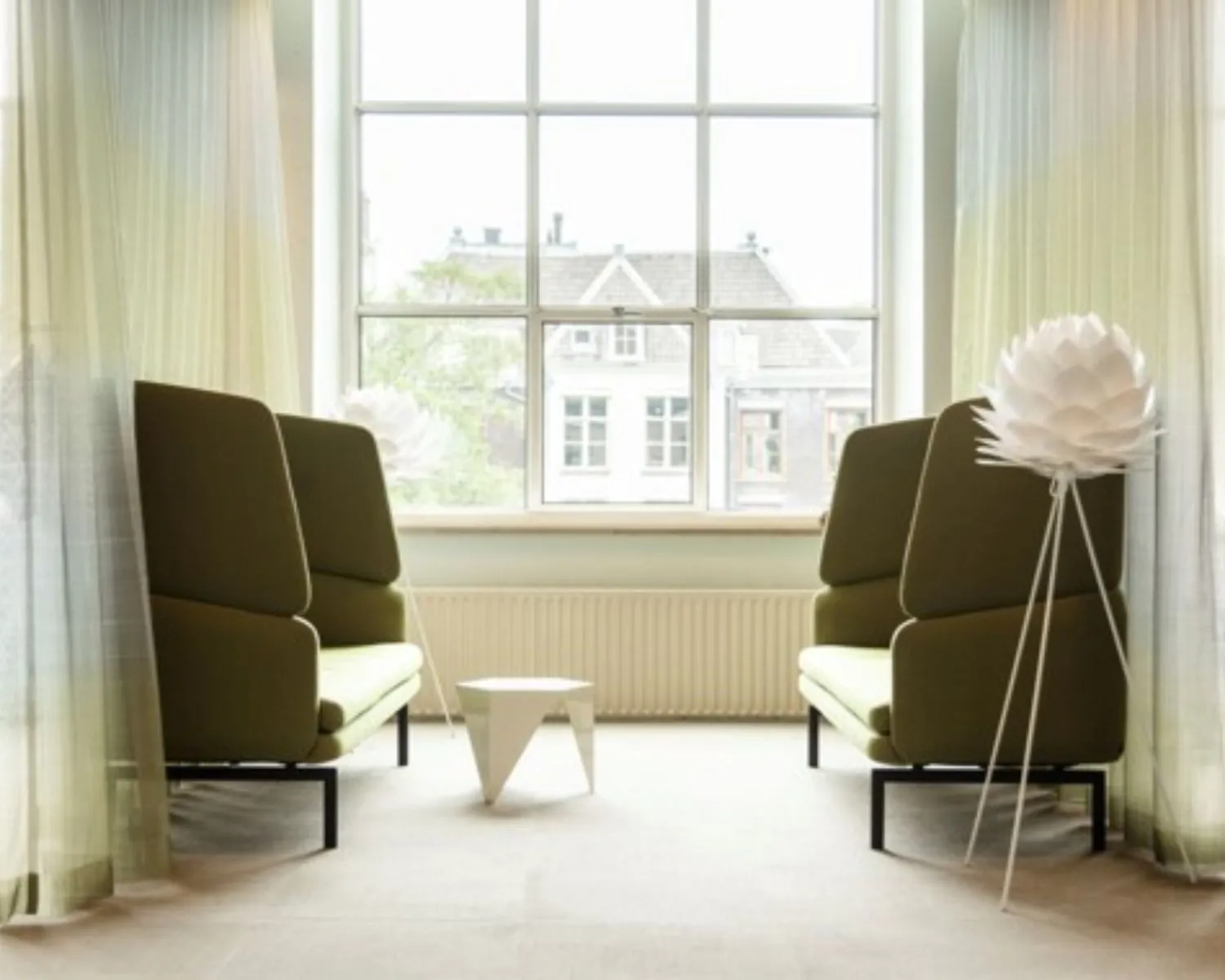 Moderne zithoek met groene banken en een witte designlamp in een kantoorruimte aan de Keizersgracht in Amsterdam.