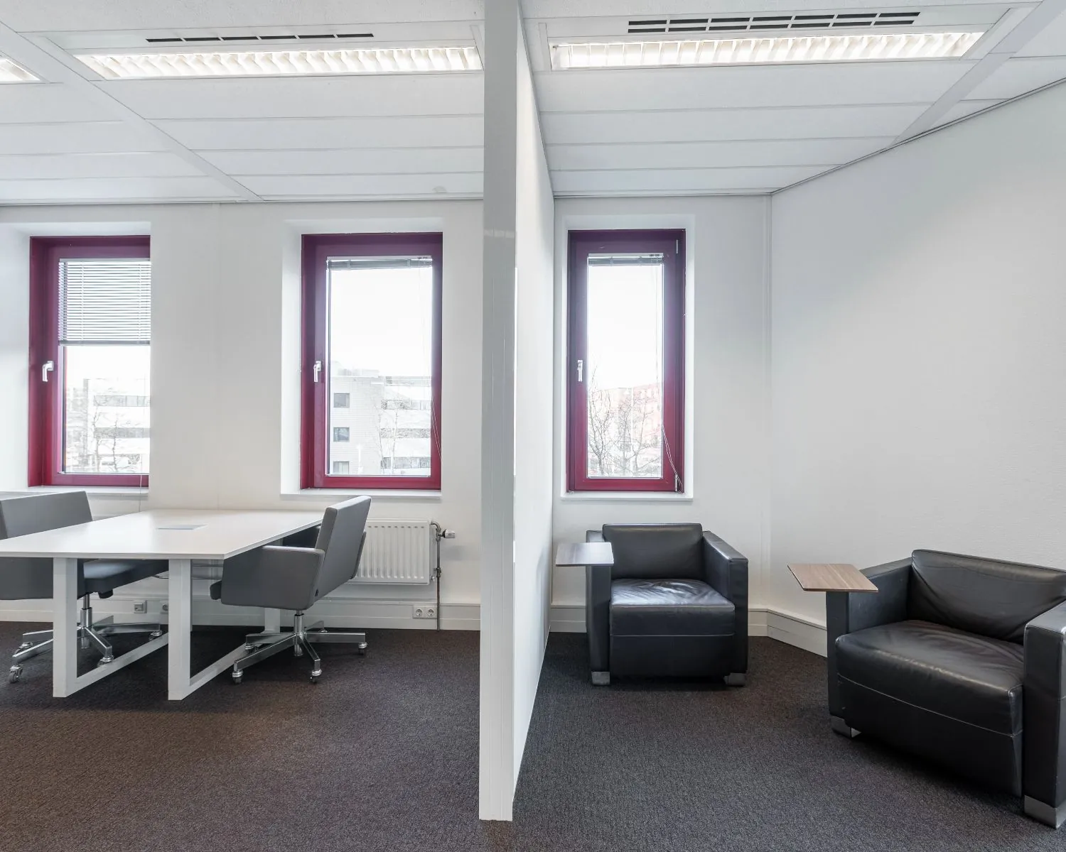 Moderne kantoorruimte aan de Kingsfortweg 151 in Amsterdam met werkplekken en loungehoek gescheiden door een wand.