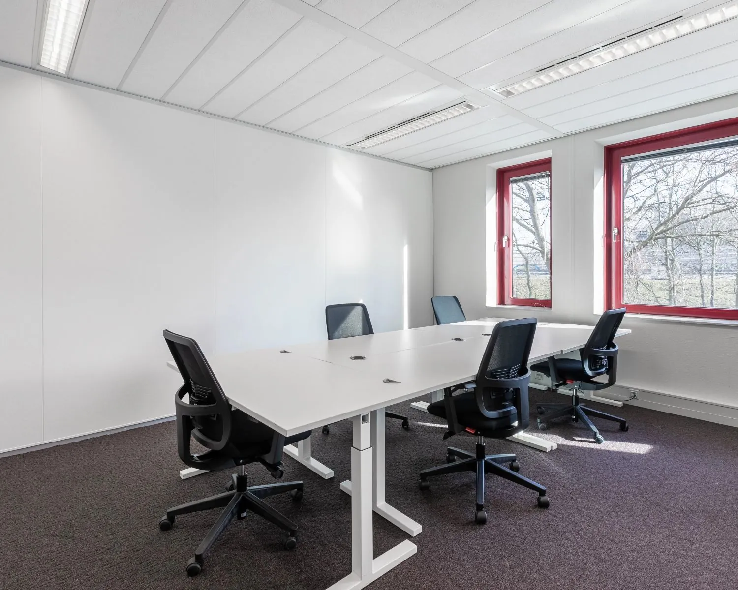 Moderne kantoorruimte met vier bureaustoelen en grote ramen aan de Kingsfortweg 151 in Amsterdam.