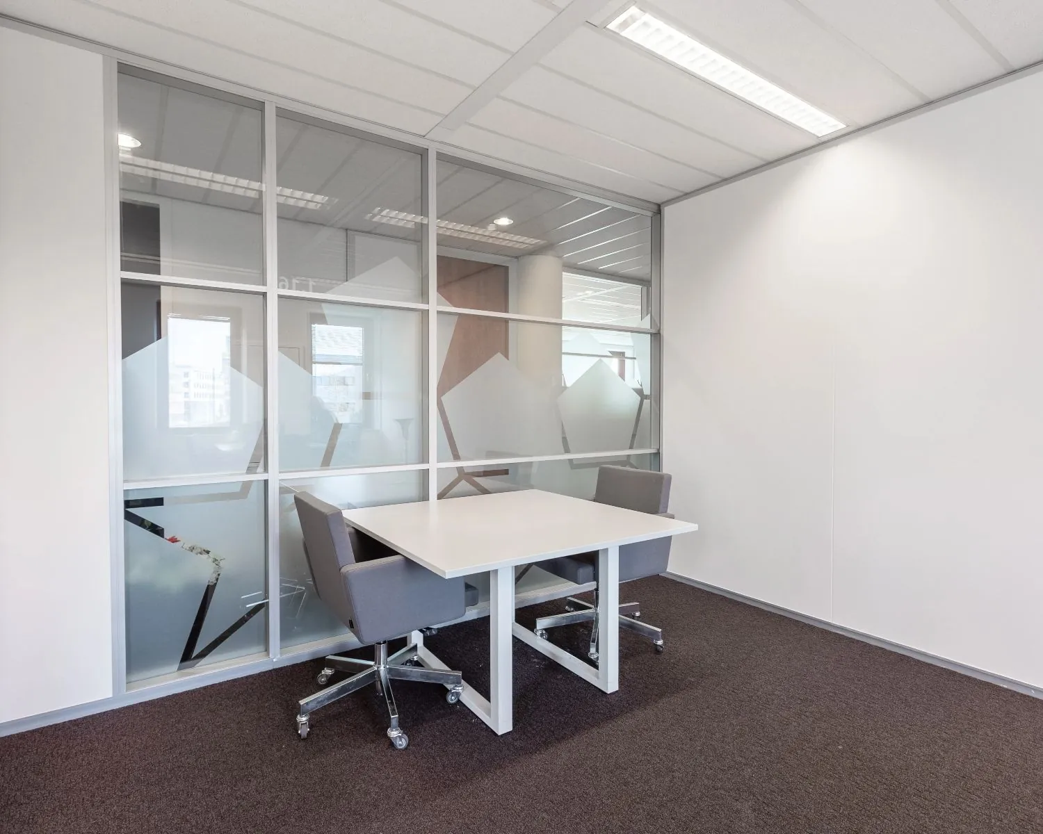 Moderne kantoorruimte met twee grijze stoelen en een witte vergadertafel aan de Kingsfortweg 151 in Amsterdam.