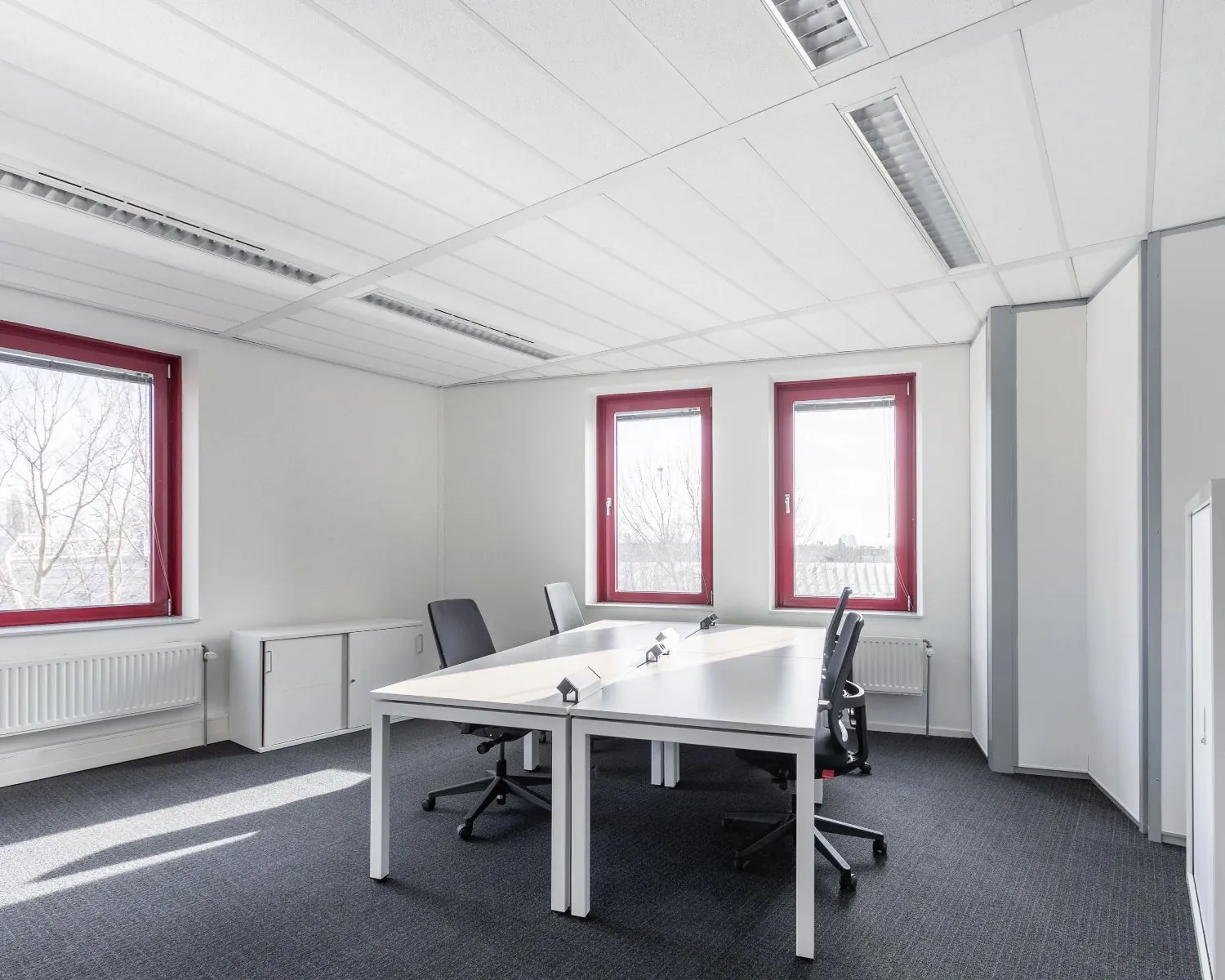 Moderne kantoorruimte met twee bureaus en rode kozijnen aan de Kingsfortweg 151 in Amsterdam.