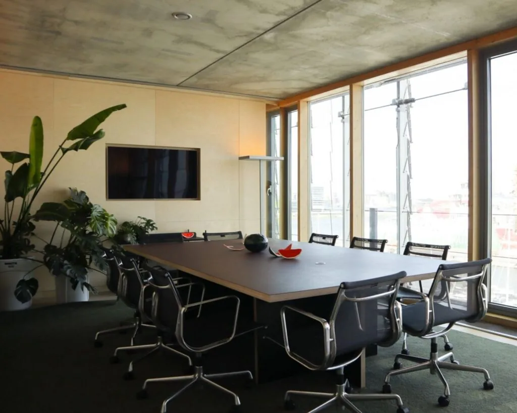 Moderne vergaderruimte in kantoor aan Kraanspoor 12 in Amsterdam met een lange tafel, designstoelen, grote ramen en veel natuurlijk licht.