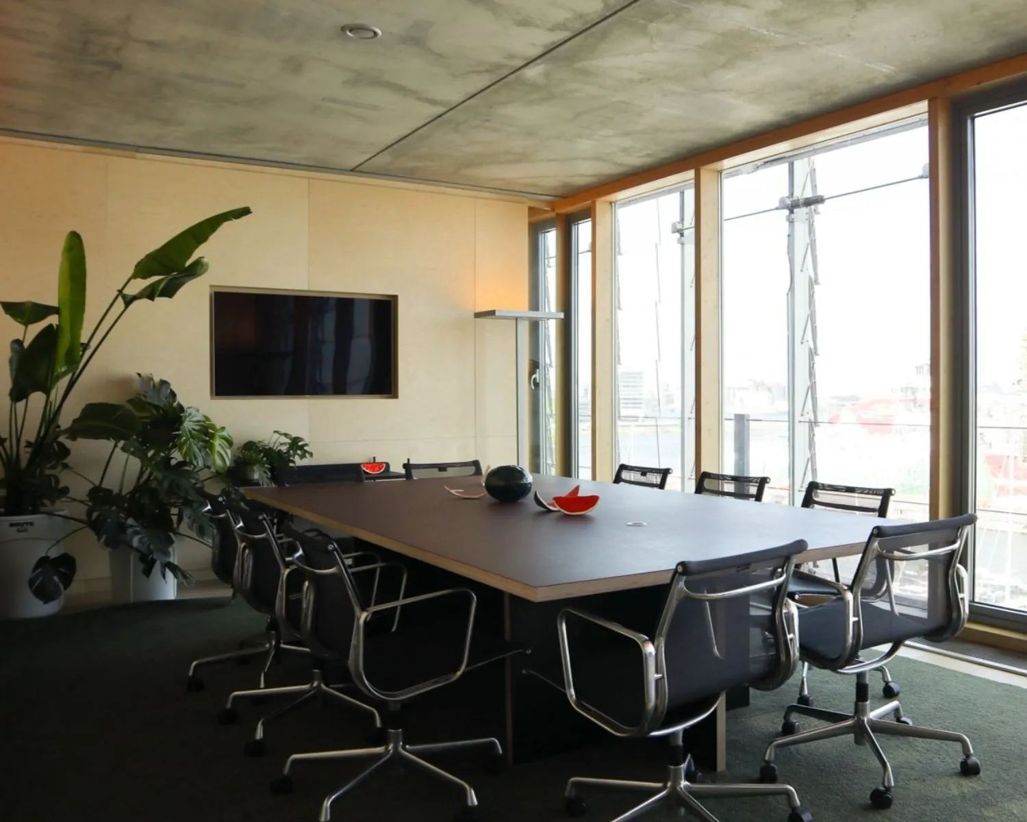 Moderne vergaderruimte in kantoor aan Kraanspoor 12 in Amsterdam met een lange tafel, designstoelen, grote ramen en veel natuurlijk licht.