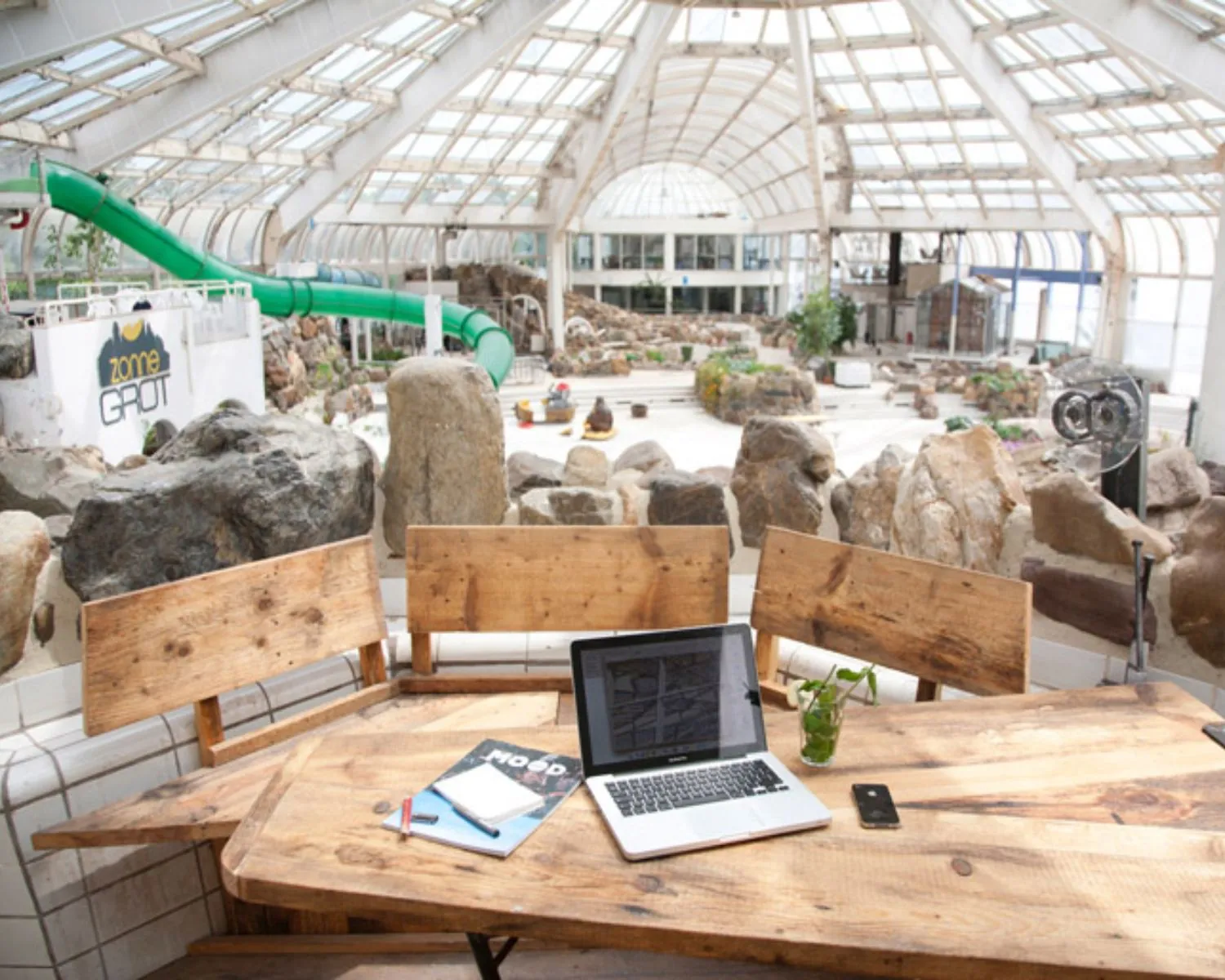 Houten vergadertafel met laptop in creatieve kantoorruimte in voormalige tropische zwemhal aan de Maasboulevard 100 in Rotterdam.