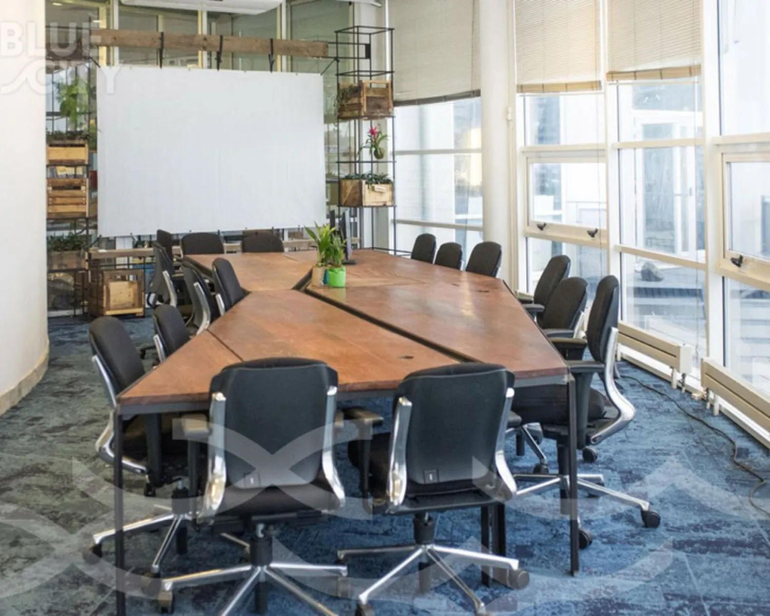 Vergaderruimte met grote houten tafel en bureaustoelen in BlueCity aan de Maasboulevard 100 in Rotterdam.