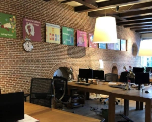 Moderne kantoorruimte aan het Molenpad 3 in Amsterdam met bakstenen muren, houten balkenplafond en meerdere werkplekken.