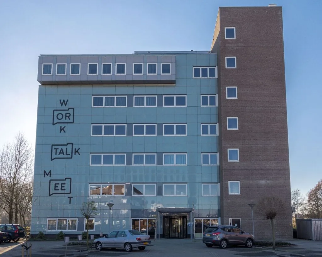 Voorgevel van een modern kantoorgebouw aan de Mr. E.N. van Kleffenstraat 6 in Arnhem met de woorden "WORK", "TALK" en "MEET" op de gevel.