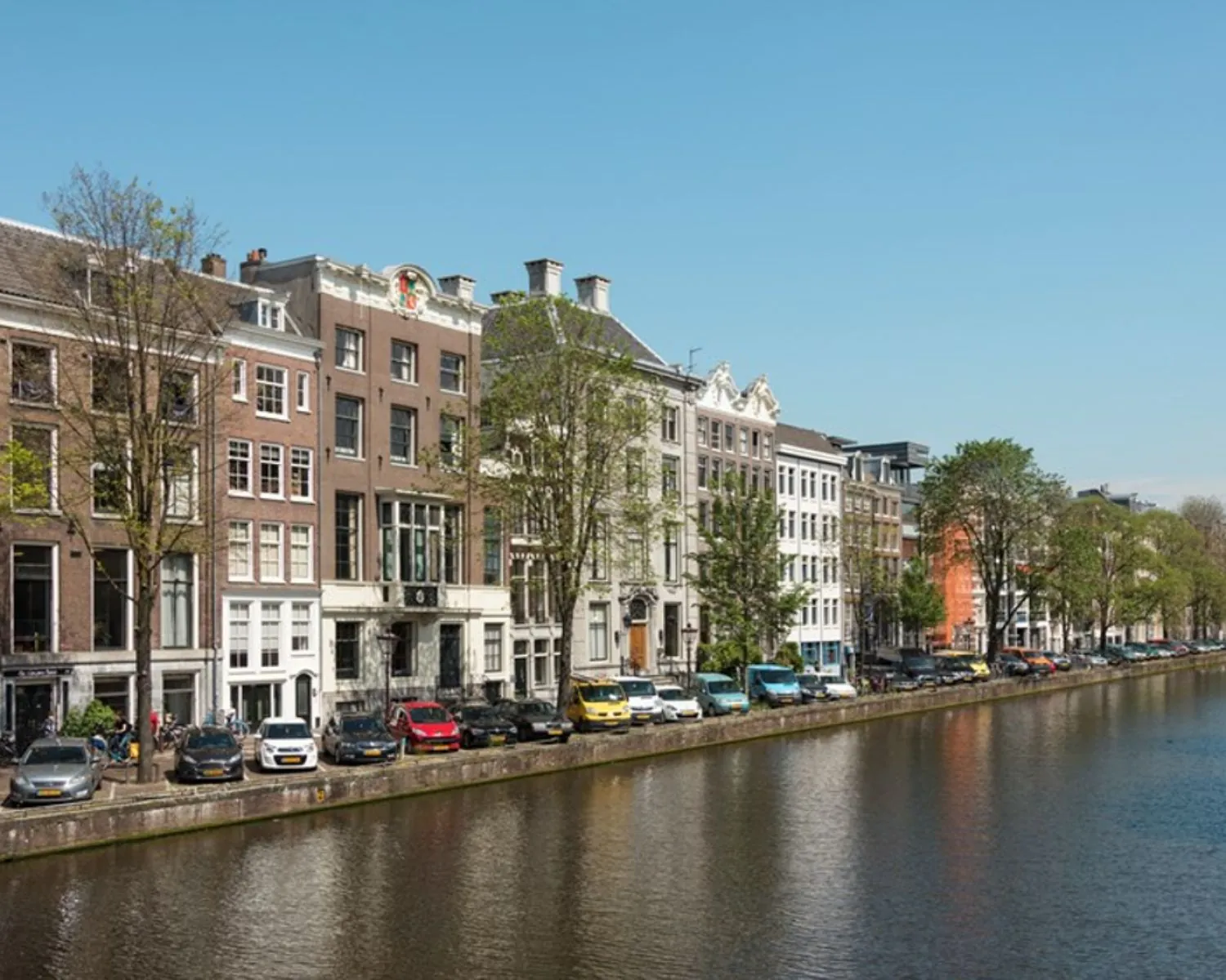 Gevelaanzicht van kantoorgebouwen aan de Nieuwe Herengracht in Amsterdam met uitzicht op de gracht.
